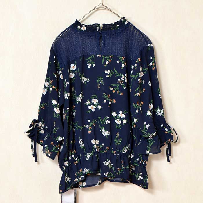 Mikonosublue Storeのネイビー花柄ジョーゼットブラウス。デコルテのシアーレースと袖口のリボンが上品な七分袖トップス。