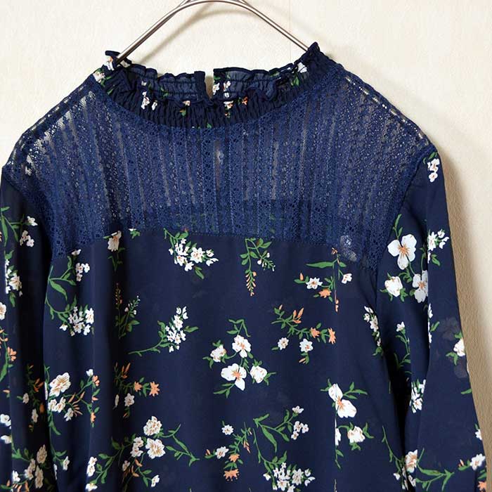 Mikonosublue Storeのネイビー花柄ジョーゼットブラウス。デコルテの繊細なシアーレースと上品なフリルネックが特徴のフェミニンな七分袖トップス。