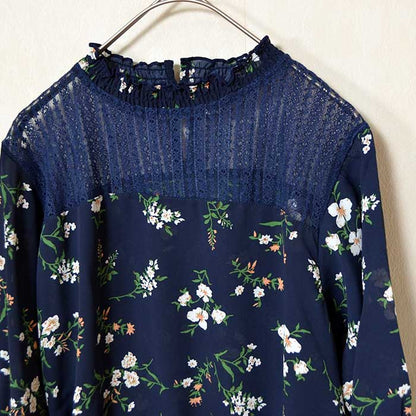 Mikonosublue Storeのネイビー花柄ジョーゼットブラウス。デコルテの繊細なシアーレースと上品なフリルネックが特徴のフェミニンな七分袖トップス。