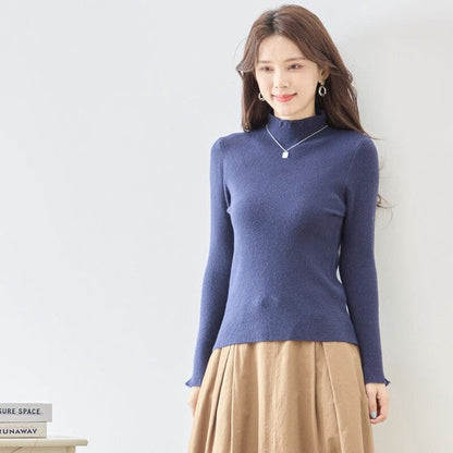 Mikonosublue Storeのネイビーのリブニットプルオーバー。ハイネックと袖口のフリルが特徴のフェミニンな長袖インナー。