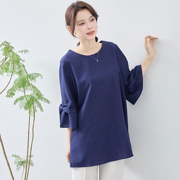 Mikonosublue Storeの袖リボン付きネイビー七分袖チュニック。ふんわりとしたAラインシルエットで体型カバーも叶う上品なブラウス。