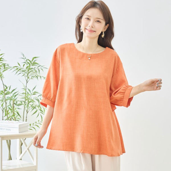 Mikonosublue Storeのオレンジ色のバックフリルトップス。ゆったりとしたAラインシルエットと5分袖で二の腕をカバーする夏用ブラウス