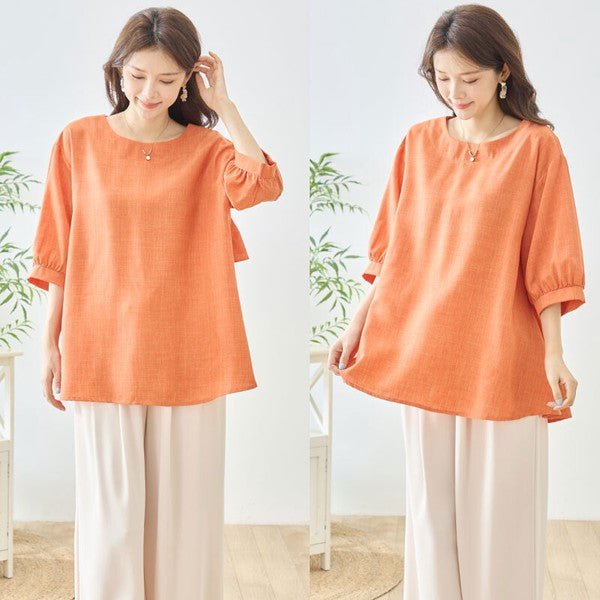 Mikonosublue Storeのオレンジ色のバックフリルトップス。ゆったりとしたAラインシルエットで5分袖の夏用ブラウス。