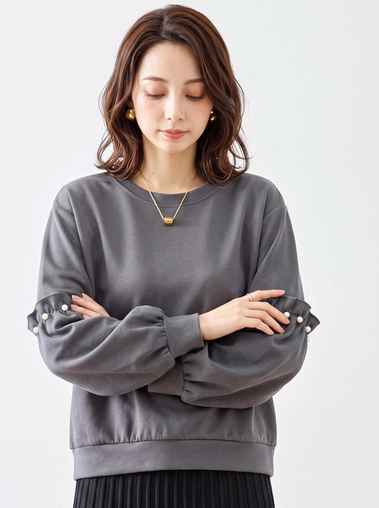 Mikonosublue Storeの袖にパールとフリルをあしらったボリューム袖のグレープルオーバーを着用した女性