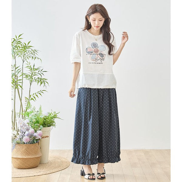 Mikonosublue Storeのピンドット柄ワイドパンツ。裾のフリルが可愛らしいネイビーのポリエステル製パンツを着用した女性。