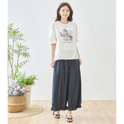 Mikonosublue Storeの裾にフリルをあしらったネイビーのピンドット柄ワイドパンツを着用した女性