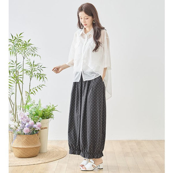 Mikonosublue Storeのピンドット柄ワイドパンツ。裾のフリルが特徴的なポリエステル素材のゆったりとしたボトムスを着用した女性。