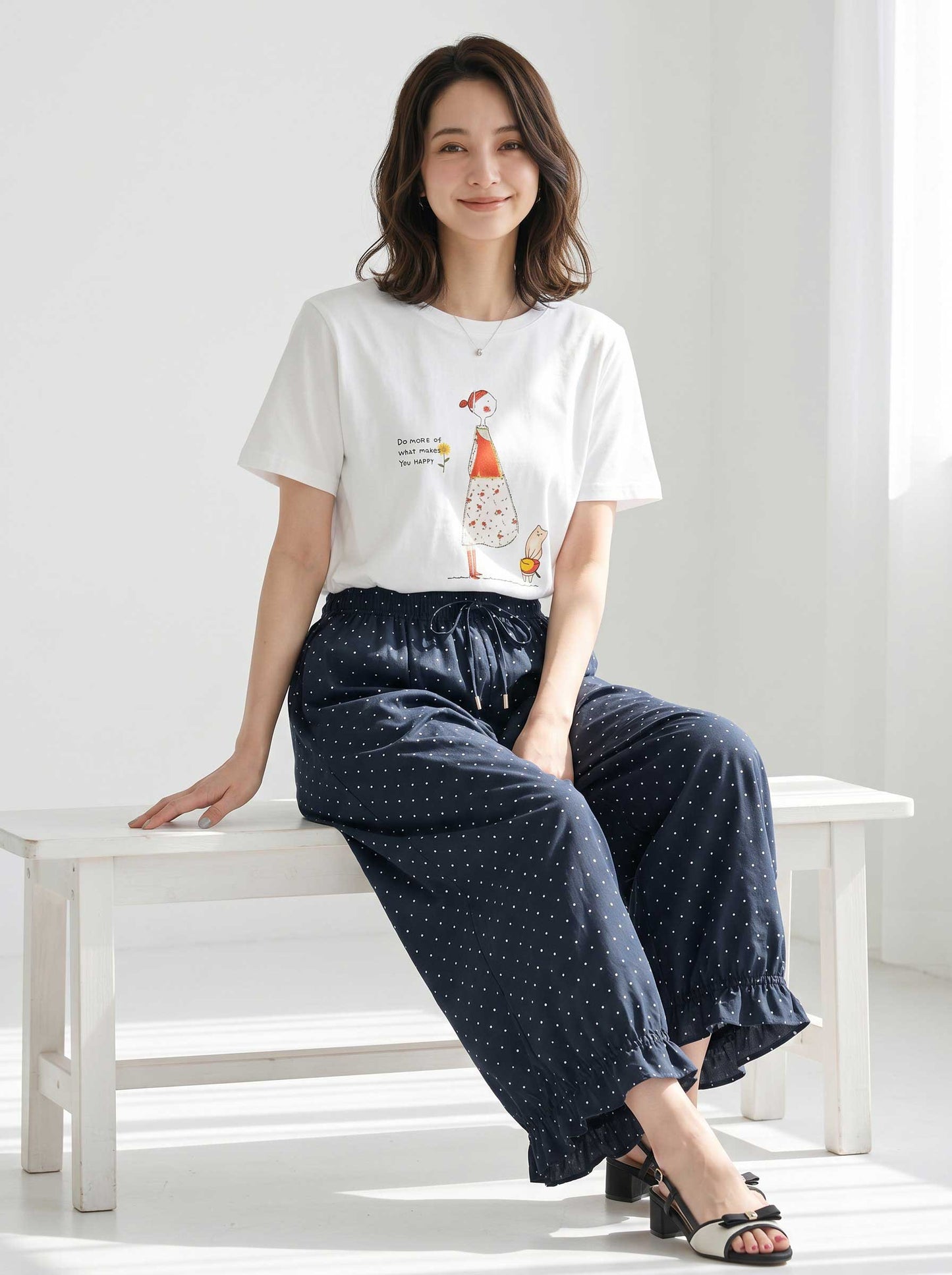 Mikonosublue Storeのネイビー地に白のピンドット柄が上品な、裾フリル付きワイドパンツを着用した女性