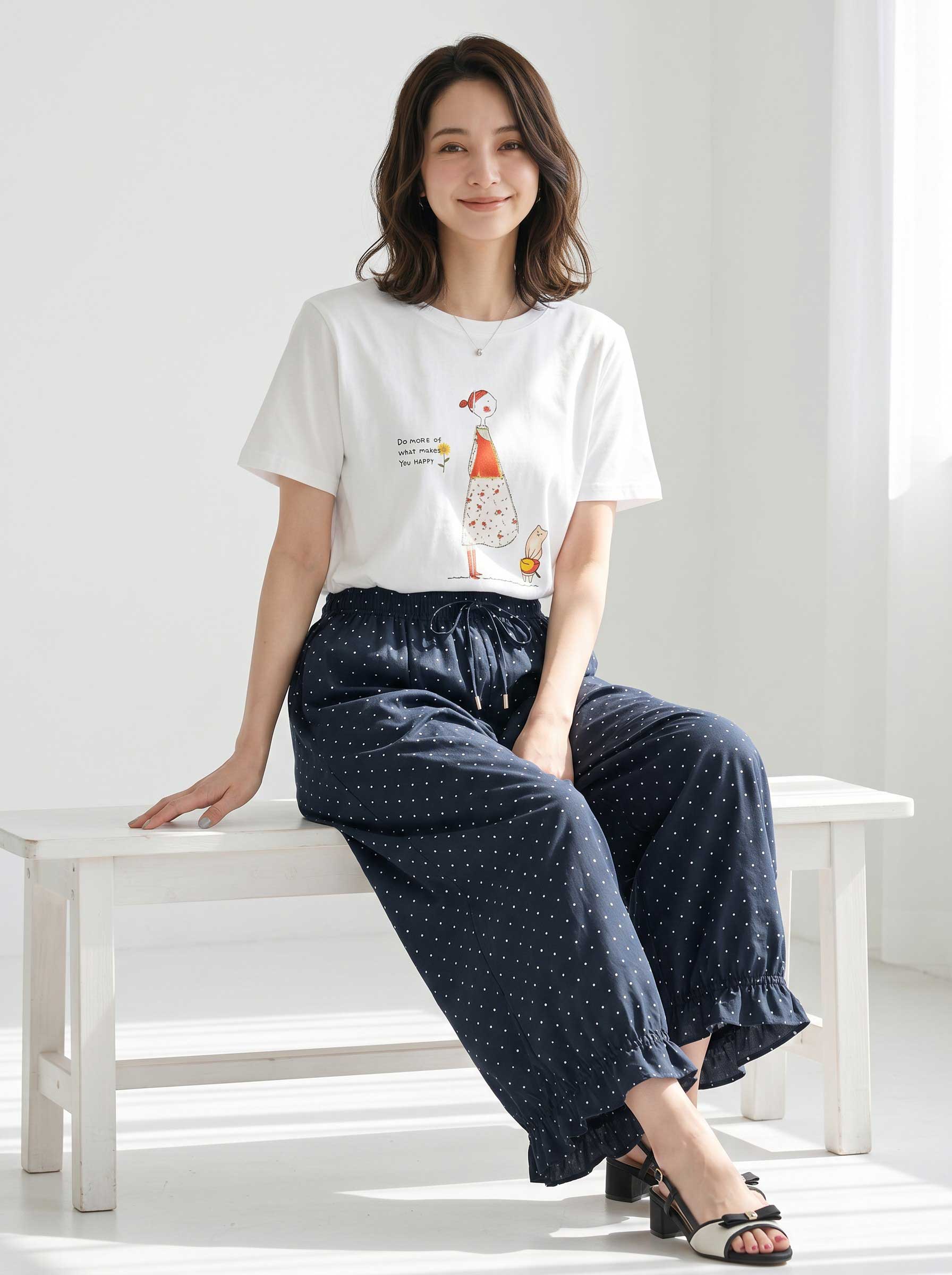 Mikonosublue Storeのネイビー地に白のピンドット柄が上品な、裾フリル付きワイドパンツを着用した女性