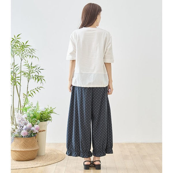 Mikonosublue Storeのピンドット柄ワイドパンツ。裾のフリルが特徴的なネイビーのポリエステル製パンツを着用した女性のバックショット。