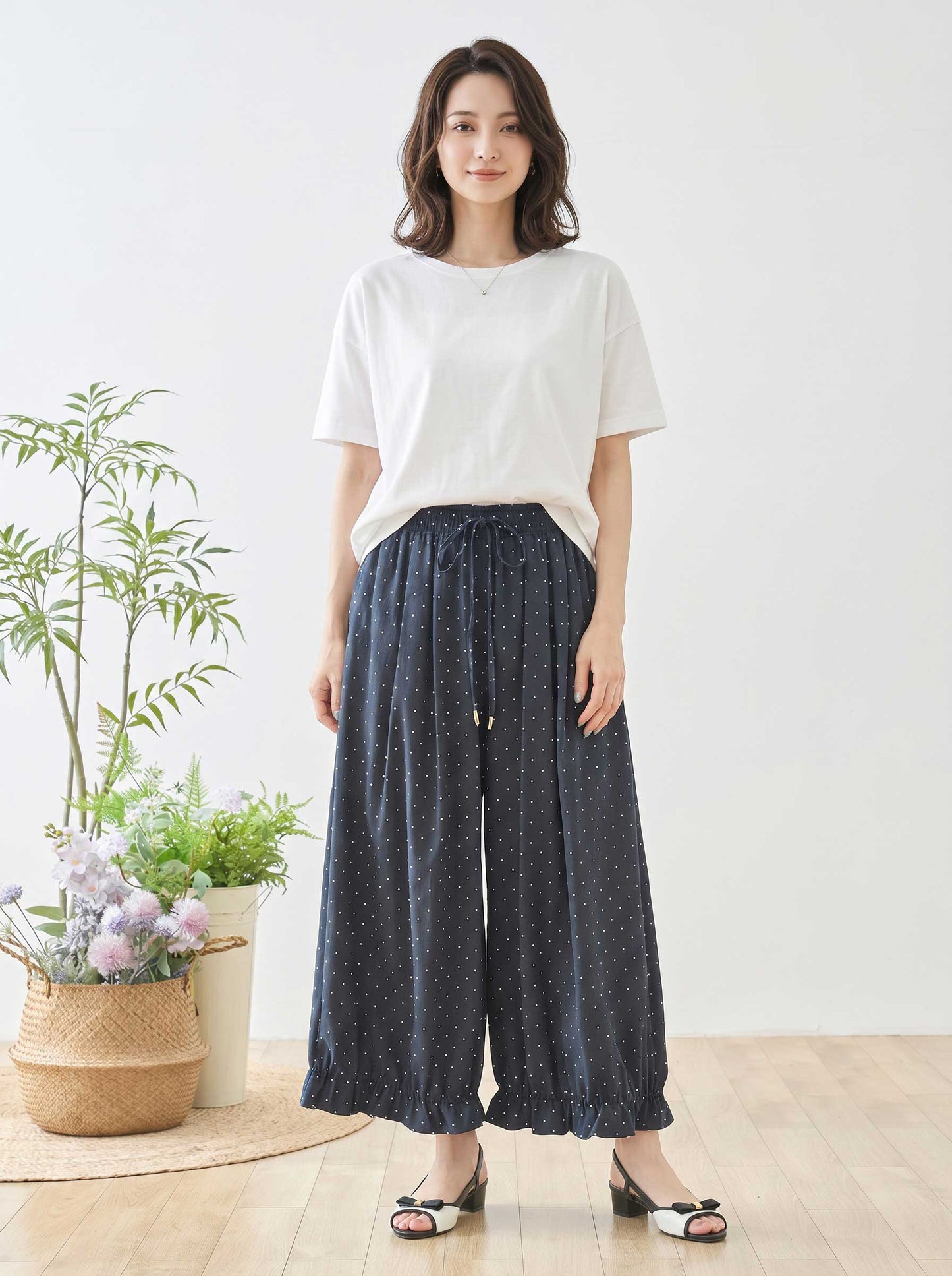 Mikonosublue Storeのピンドット柄ワイドパンツ。裾のフリルとゆったりしたシルエットが特徴のネイビーのポリエステル製パンツを着用した女性。