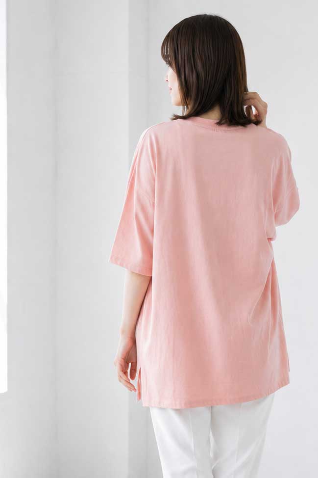 Mikonosublue Storeのピンク色のゆったりとした綿100%半袖Tシャツを着用した女性のバックスタイル