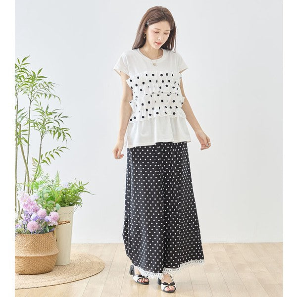 Mikonosublue Storeのポルカドット柄ワイドパンツ。裾に白いクロシェレースをあしらった黒のゆったりとしたシルエットで、モデルがフェミニンに着こなしています。