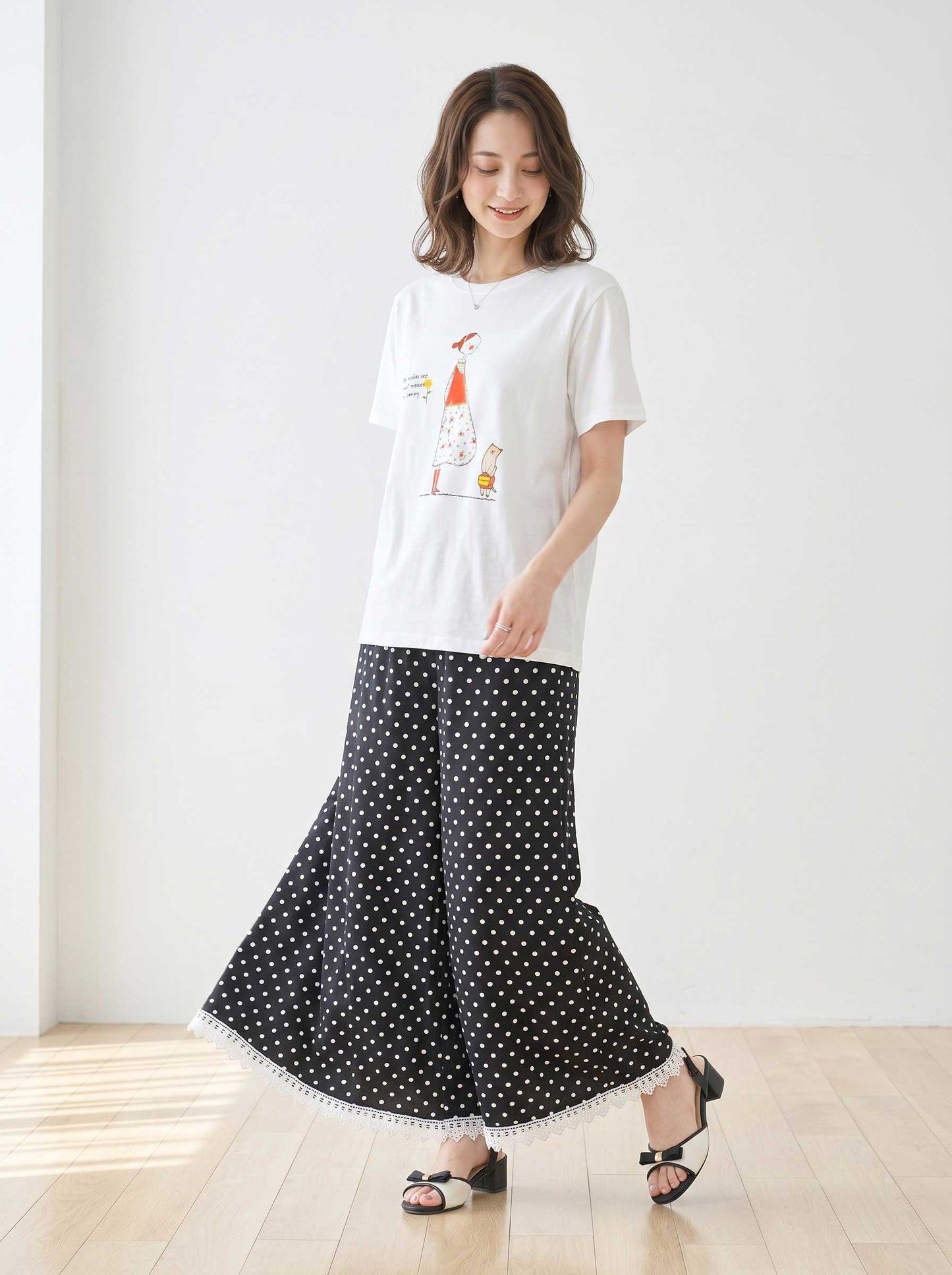 Mikonosublue Storeのポルカドット柄ワイドパンツ。裾に白いクロシェレースをあしらった黒のゆったりとしたパンツを着用した女性。