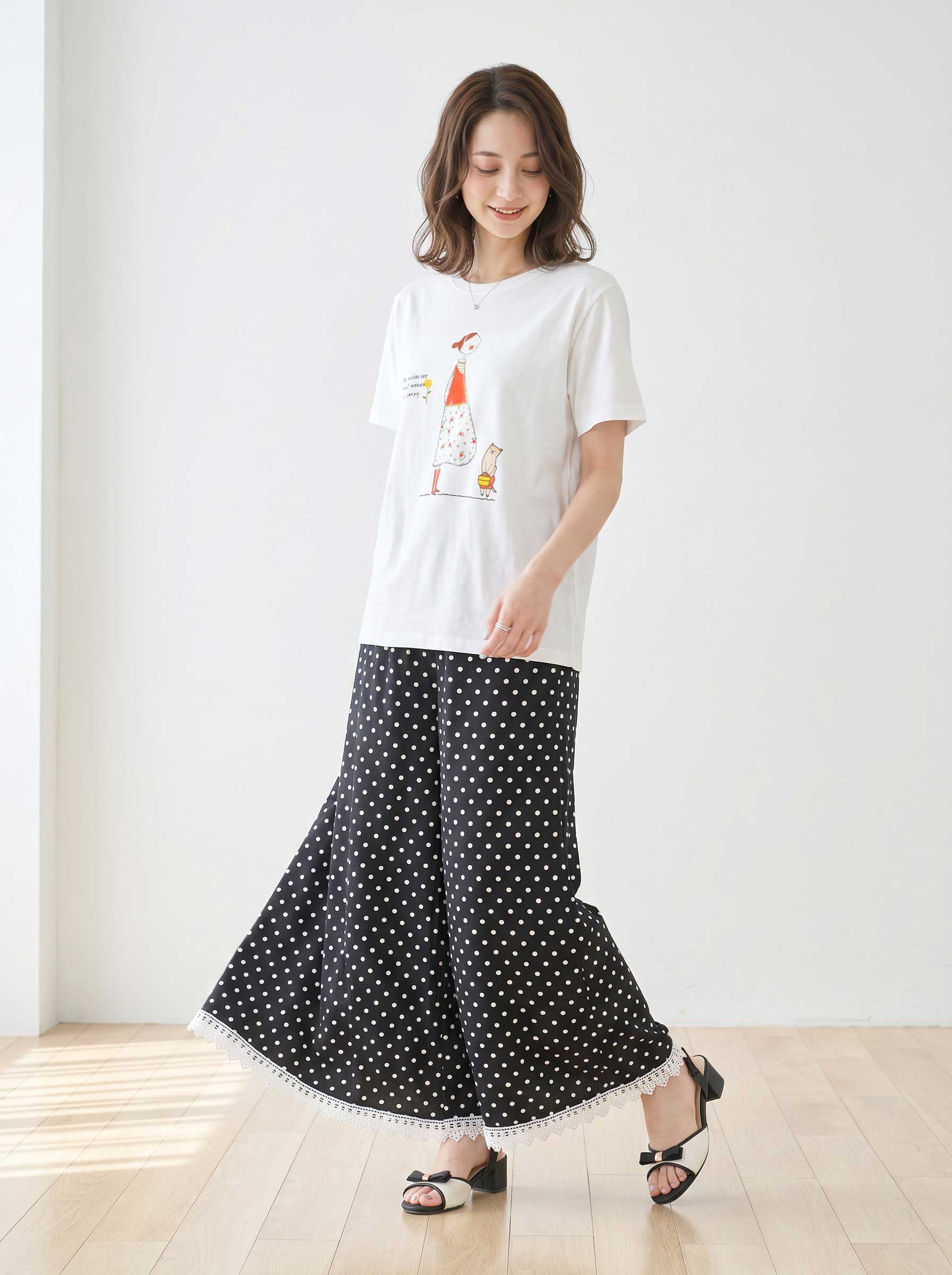 Mikonosublue Storeのポルカドット柄ワイドパンツ。裾に白いクロシェレースをあしらった黒のゆったりとしたパンツを着用した女性。