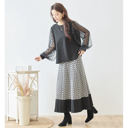 Mikonosublue Storeのパールとドット柄チュール袖が華やかな黒の異素材切替プルオーバーを着用した女性