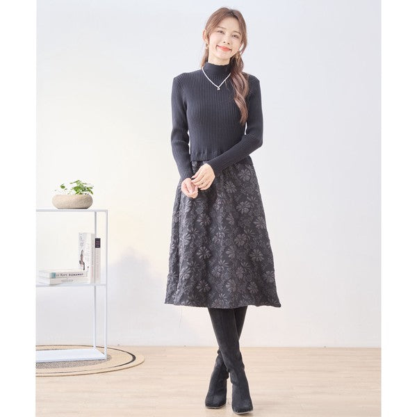 Mikonosublue Storeの黒いリブニットと花柄ふくれジャガードスカートをドッキングした長袖ワンピースを着用した女性