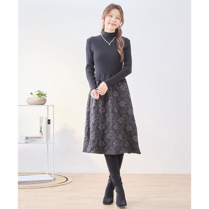 Mikonosublue Storeの黒いリブニットと花柄ふくれジャガードスカートをドッキングした長袖ワンピースを着用した女性