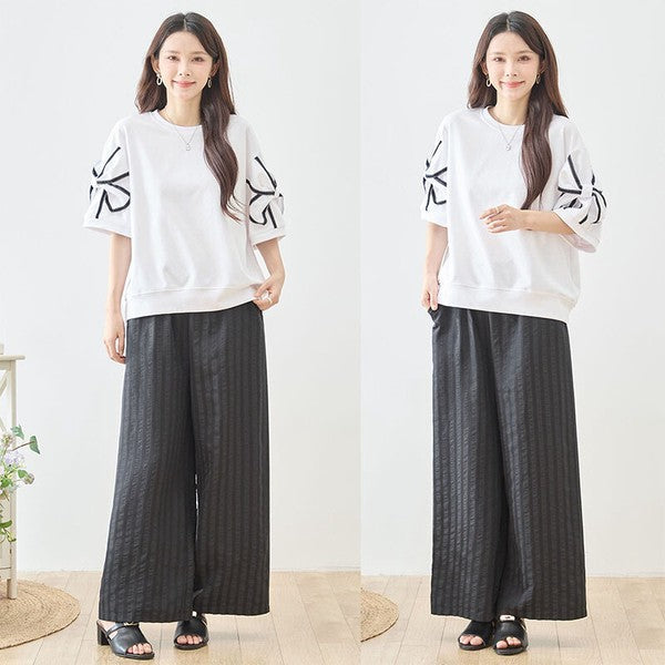 Mikonosublue Storeのストライプ柄ワイドパンツを着用した女性。ウエストゴムでゆったりとした美脚シルエット。