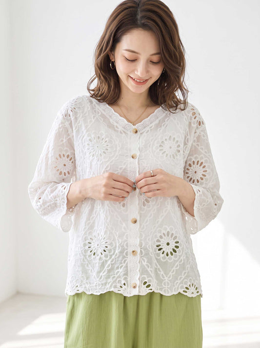 Mikonosublue Storeの白いコットン製カットワーク刺繍ブラウス。Vネックと七分袖で、花柄の透かし模様が涼しげなデザイン。