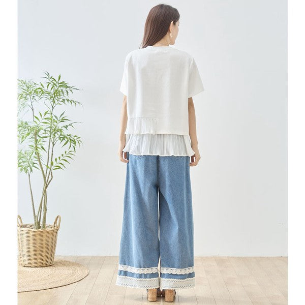 Mikonosublue Storeの裾にアシンメトリーなプリーツフリルをあしらったホワイトの半袖Tシャツを着用した女性のバックスタイル