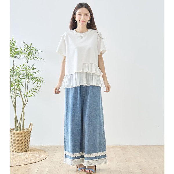 Mikonosublue Storeの裾にアシンメトリーなプリーツフリルをあしらったホワイトの半袖Tシャツを着用した女性