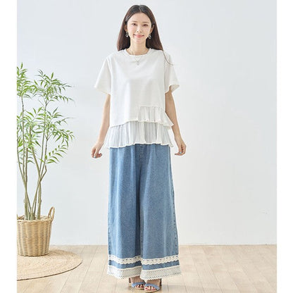 Mikonosublue Storeの裾にアシンメトリーなプリーツフリルをあしらったホワイトの半袖Tシャツを着用した女性