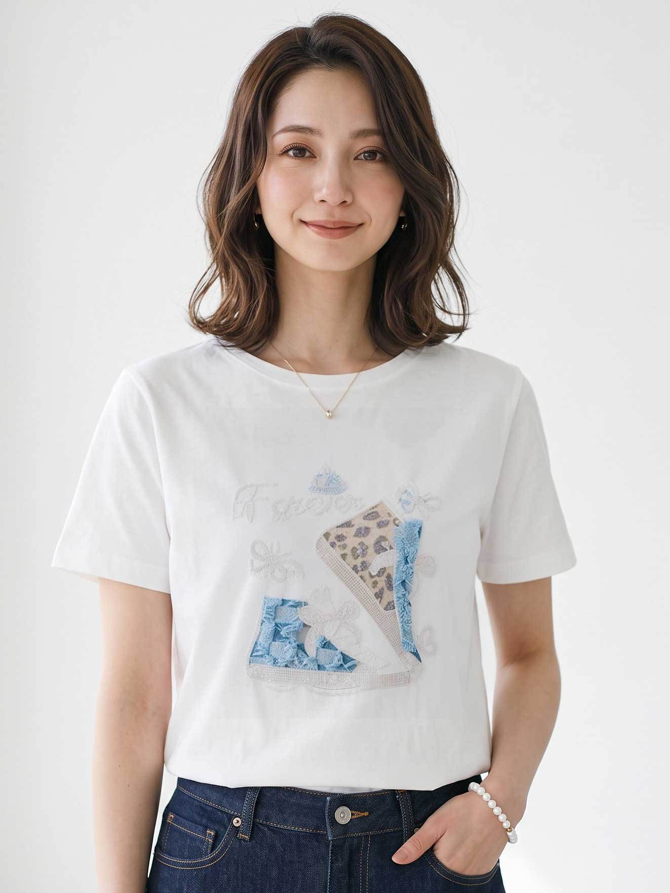 Mikonosublue Storeのラインストーンと異素材パッチワークのスニーカー柄が施された、ゆったりとした白い半袖コットンTシャツを着用した女性