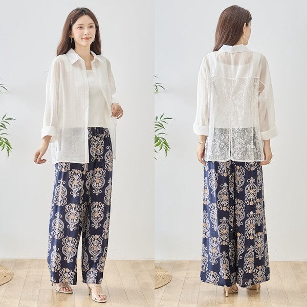 Mikonosublue Store white sheer long-sleeve blouse with floral lace paneling and a relaxed fit, worn by a model with patterned navy pants.