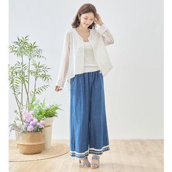 Mikonosublue Storeのシアー素材とカットワークレースを組み合わせた、バックロング丈のフェミニンなホワイトジャケットを着用した女性
