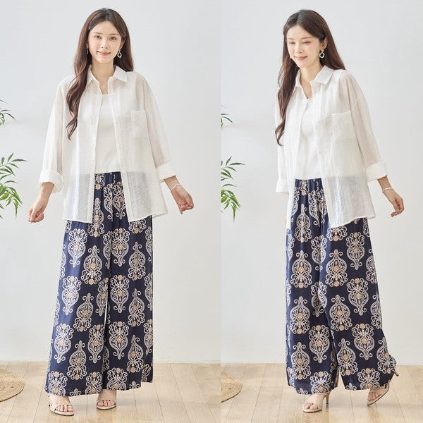 Mikonosublue Store white sheer long-sleeve shirt with floral lace details and wide-leg patterned pants.